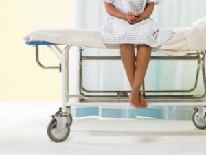 Female patient sitting on gurney in hospital gown